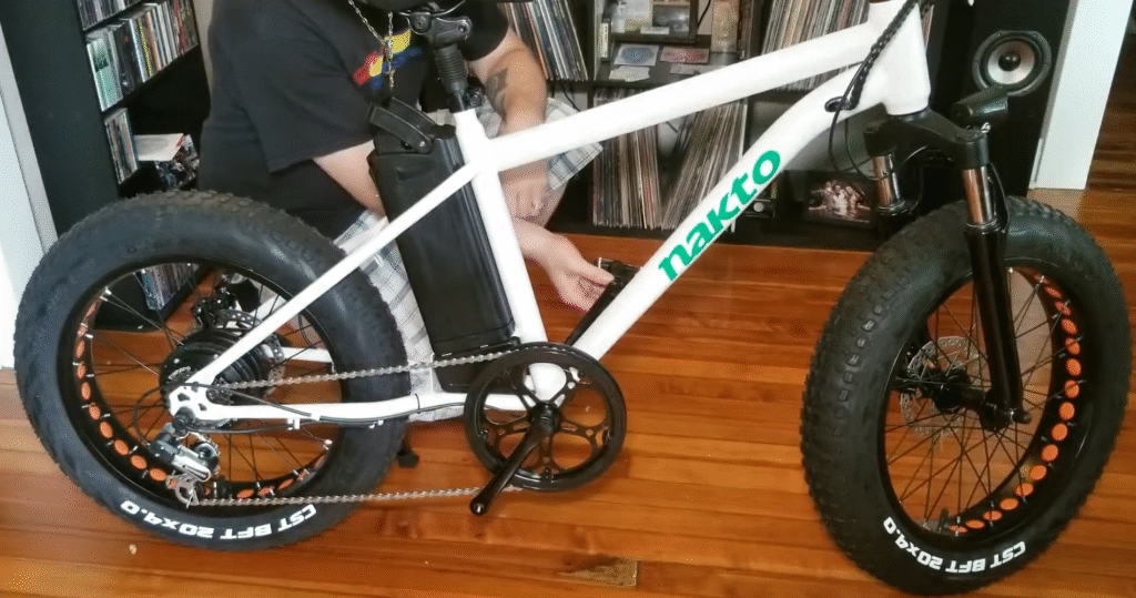 Nakto Electric Bike Reviews: Models, Value, Pros & Cons 1 Nakto fat-tire electric bike being assembled indoors, showing battery mounted on the frame and 20x4.0 CST tires.