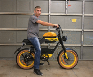A person riding a yellow and black electric bike in a garage, showcasing the HappyRun G400 model.