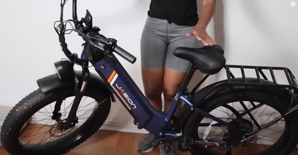 Jasion step-through fat-tire electric bike shown indoors with rear cargo rack and adjustable saddle.