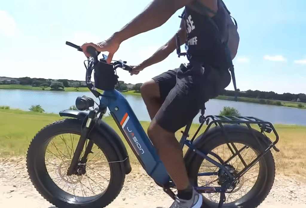 Rider test-rides a Jasion fat-tire e-bike on a lakeside trail, demonstrating pedal assist and real-world handling.