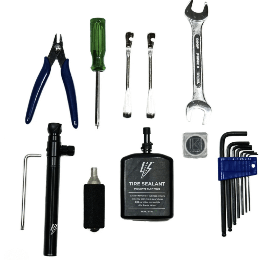 Essential toolkit for e-bike maintenance including pliers, screwdrivers, wrenches, hex keys, tire sealant, and pump.
