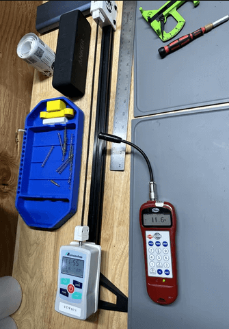 Pedal "Clunk" at Start on Belt-Drive E-Bikes: All Likely Causes & Fixes 1 Workbench with various tools including a digital multimeter displaying 11.6, a timer showing 1:45, a blue tray holding screws, a ruler, a green-handled screwdriver, and other maintenance items on a gray mat.