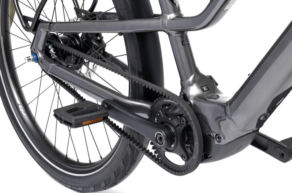 Pedal "Clunk" at Start on Belt-Drive E-Bikes: All Likely Causes & Fixes 2 Close-up view of a gray e-bike's rear drivetrain, showing a Gates carbon belt drive system connected to an Enviolo internal gear hub and a mid-drive motor, with the pedal and crank arm visible.