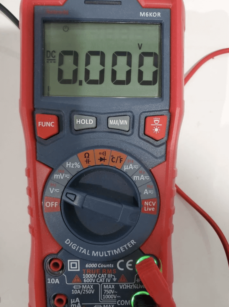 Digital multimeter displaying 0.000 volts in DC mode during an e-bike controller voltage test.
