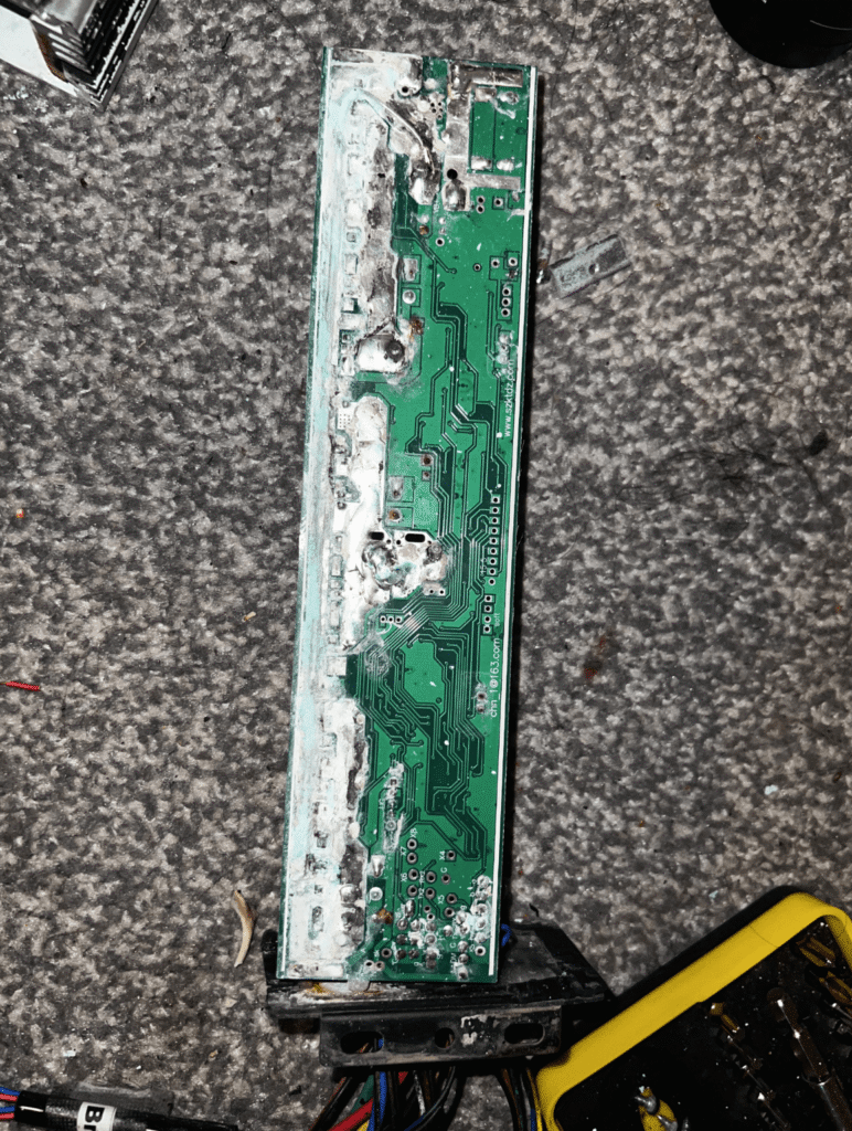 Close-up of a corroded and damaged e-bike motor controller circuit board showing burned and oxidized components.
